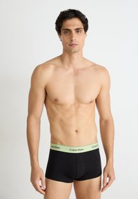 Zwarte boxershorts met een lichtgroene tailleband van Calvin Klein. Glad materiaal met een aansluitend ontwerp, dat een eenvoudige, moderne stijl toont.