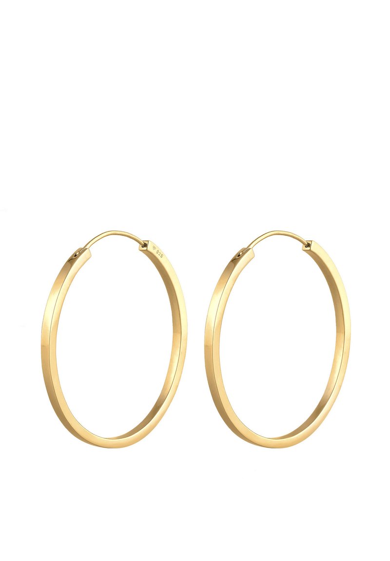 Orecchini a cerchio in tono oro con una finitura liscia e lucida, caratterizzati da una forma circolare e una chiusura a cerniera discreta. Design leggero.