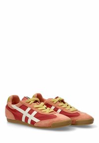 Zapatillas rojas y rosas hechas de gamuza y malla, con franjas blancas, cordones amarillos y una suela de goma marrón.