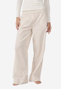 Lichte, wijde pyjamabroek in crèmekleur met dunne lila strepen. Bevat een elastische tailleband en knoopdetails aan de voorkant.