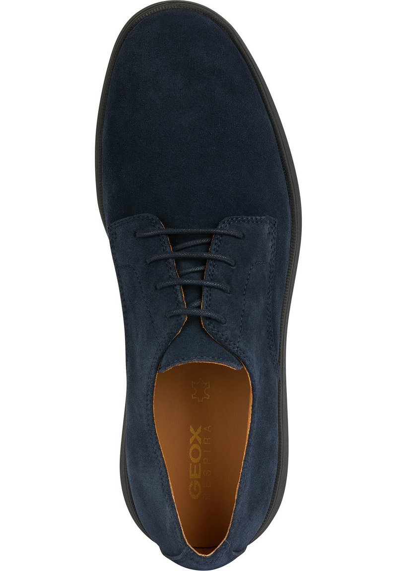 Chaussure en daim bleu marine à lacets avec un bout arrondi, semelle intérieure orange contrastante et semelle en caoutchouc noir. Présente un minimum de détails de couture.