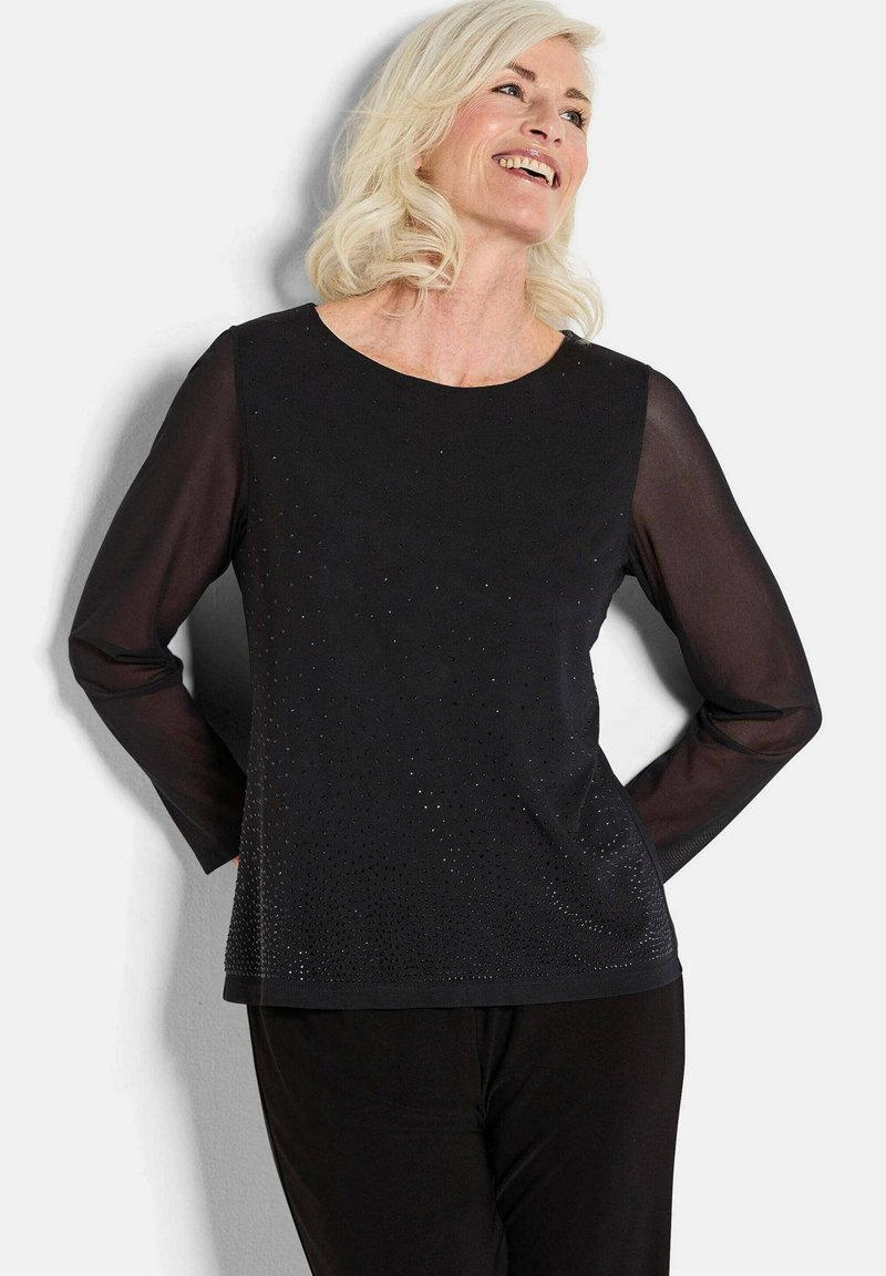 Maglietta nera a maniche lunghe con scollatura rotonda, caratterizzata da un design testurizzato con piccoli abbellimenti sul davanti e maniche trasparenti.