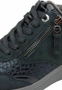 Primer plano de una zapatilla de ante negro con cordones negros, cremallera lateral y panel texturizado con un sutil estampado animal en el lateral.