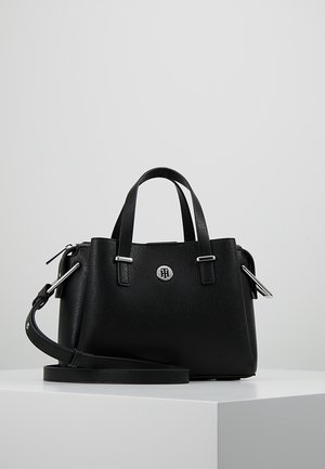 Zwarte leren handtas met een geborsteld effect, voorzien van twee handvatten, afneembare schouderriem, zilverkleurige metalen details en een rond logo-embleem aan de voorkant.