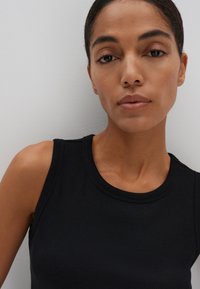 Débardeur noir à côtes avec un col rond et des bretelles larges, présentant une texture lisse et une coupe ajustée.