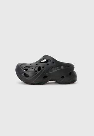 Black clogs made of molded rubber, featuring large ventilation holes, a rounded toe, textured sole, and curved heel design.