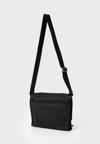 Borsa a tracolla nera realizzata in tessuto resistente, dotata di una tracolla regolabile, forma rettangolare e una tasca frontale per ulteriore spazio di archiviazione.