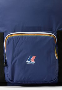 Marineblauwe rugzak met een voorvak voorzien van een witte rits en oranje-geel accent. K-Way logo prominent aanwezig. Gelaagd nylon materiaal.
