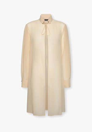 Abito camicia crema a maniche lunghe con collo alto, dettagli con bottoni e chiusura frontale con laccio, in una vestibilità ampia e dritta.