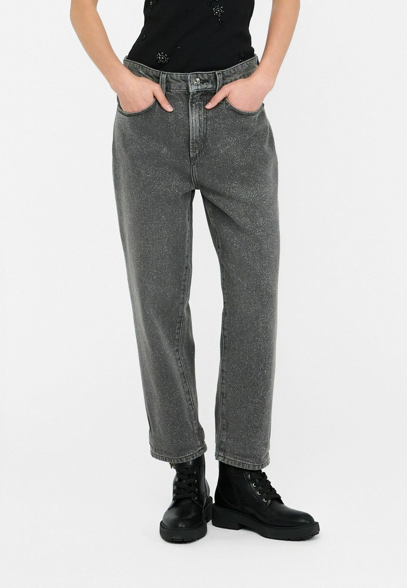 Jeans in denim grigio con una vestibilità ampia, gamba diritta, vita alta, caratterizzati da tasche frontali e una leggera texture marmorizzata, abbinati a stivali militari neri.