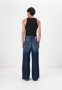 Mörkblå vida jeans med en blekt textur och detaljer med bakfickor, kombinerat med en figurnära svart linne.