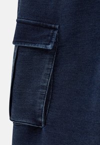 Dunkelblaue Cargo-Shorts mit einer seitlichen aufgesetzten Tasche, detaillierter Naht und einem strukturierten Stoff mit einem dezenten Muster.