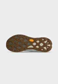 Semelle d'une chaussure avec une bande de roulement en caoutchouc marron présentant des motifs en forme de croix et un petit logo jaune près du centre.