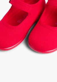 Zapatos de lona rojos con punta redonda y una correa, que cuentan con una suela de goma suave y tela texturizada para mayor agarre y comodidad.