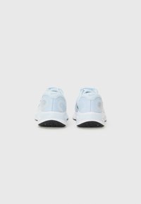 Helle blaue Sportschuhe mit weißer Sohle, von hinten betrachtet, die die strukturierte Oberfläche und das Nike-Logo auf jeder Ferse zeigen.
