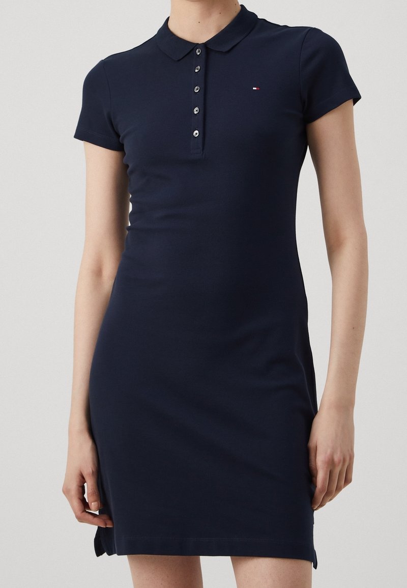 Vestido polo azul marino hecho de algodón elástico, con cierre de botones, mangas cortas y un pequeño logo en el pecho.