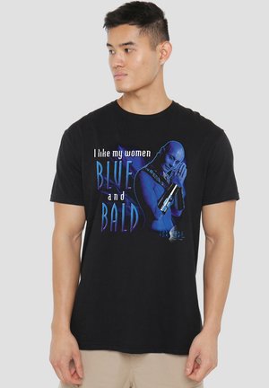 Young man wearing black t-shirt with blue-skinned bald character and text "I like my women blue and bald" on the front.