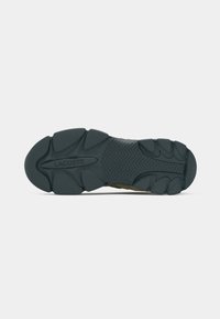 Sole of a shoe in black rubber with textured tread pattern and raised sections. Includes "LACOSTE" logo imprinted on the midsole.