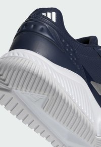 Granatowy but sportowy z fakturowaną cholewką, smukłym designem i białą gumową podeszwą z wyraźnymi rowkami dla lepszej przyczepności.