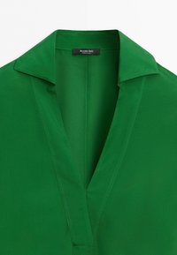 Green shirt with a wide collar and deep V-neck, showing the inside label that reads "Massimo Dutti Made in China."