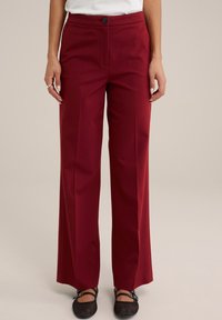 Burgundy vidbenade byxor i slät tyg med framknäppning, skräddarsydda linjer och kontrasterande platta fickor.