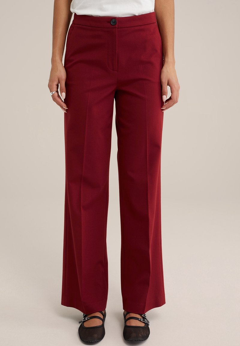 Burgundy vidbenade byxor i slät tyg med framknäppning, skräddarsydda linjer och kontrasterande platta fickor.