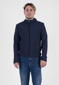 Giacca leggera di colore blu navy con cappuccio, chiusura con zip completa e tasche laterali. Texture liscia, design attillato e branding discreto sulla manica.