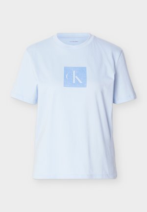 Camiseta de algodón azul claro con un logotipo gráfico cuadrado en un azul más oscuro. Mangas cortas y escote redondo con un corte relajado.