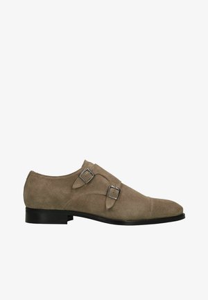 Beige suède herenschoen met dubbele monkstrap, twee zilverkleurige metalen gespen en zwarte zool, getoond in zijprofiel van rechts.