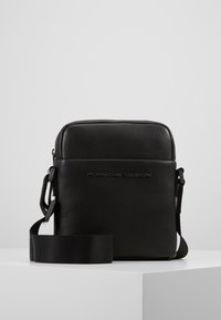 Czarna skórzana torba na ramię z teksturowanym wykończeniem, z suwakiem i regulowanym paskiem, z wytłoczonym logo "Porsche Design".