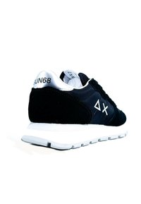 Scarpa da ginnastica nera con materiali in suede e mesh, suola in gomma bianca, dettagli argentati sul tallone, con logo del marchio e dettagli di cucitura.