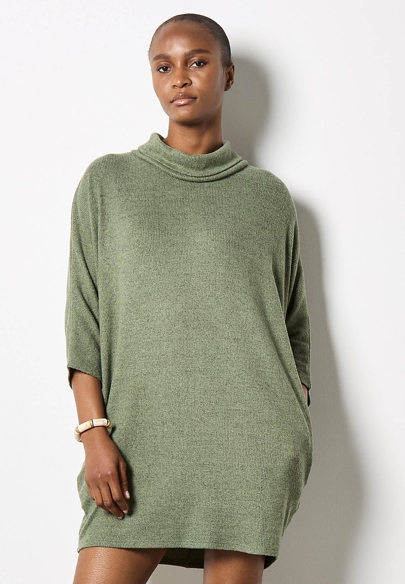 Abito in maglia oversized color verde oliva, con collo a cowl, maniche corte, tessuto testurizzato e tasche laterali.