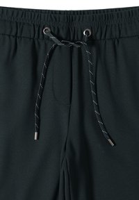 Černé sportovní kalhoty s elastickým pasem, s tkaničkou se stříbrnými konci a jemnou texturou. Žádné viditelné kapsy.