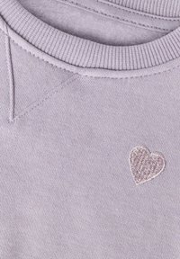 Jasnofioletowa bluza z prążkowanym, okrągłym dekoltem i małym haftowanym serduszkiem w jaśniejszym odcieniu fioletu na piersi.