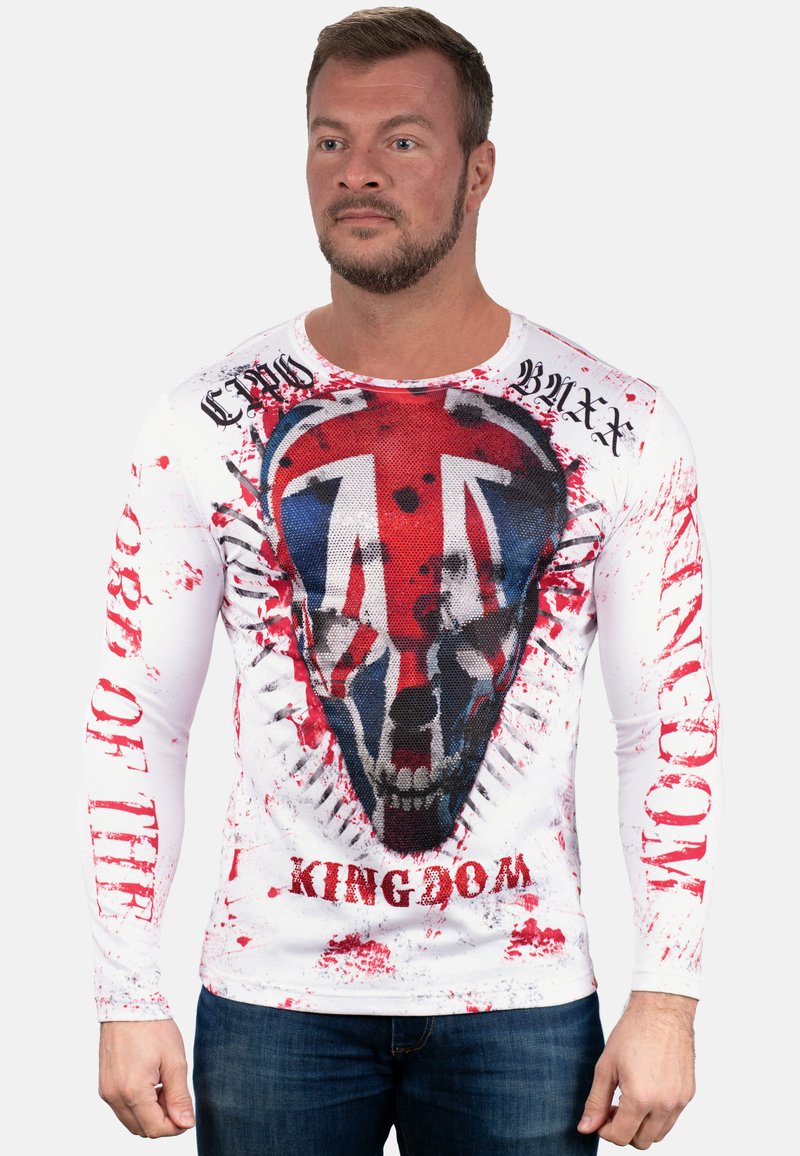 Witte t-shirt met lange mouwen waarop een graphic van een schedel is afgebeeld, met een Union Jack ontwerp, rode spetterpatronen en vetgedrukte zwarte tekst.