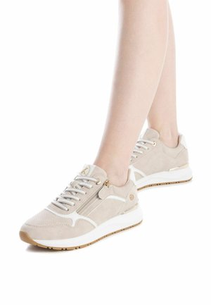 Zapatillas de ante beige con acentos blancos, detalle de cremallera metálica y superficie texturizada. Presentan cordones planos y una suela acolchada.
