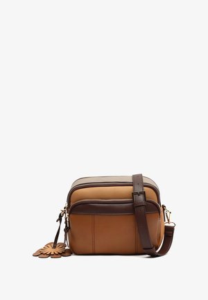 Brown and tan leather crossbody bag with zipper closure, adjustable strap, and a flower-shaped leather accent attached.
