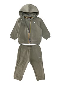 Tuta verde oliva con felpa con zip e pantaloni coordinate. Tessuto morbido, polsini a coste e dettagli del logo su entrambi i pezzi.