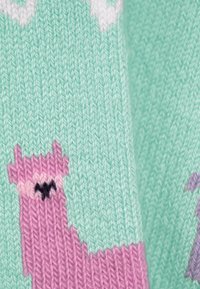 Maglieria con uno sfondo verde menta e un design di lama rosa. La texture è morbida, con colori contrastanti e dettagli di cucitura discreti.