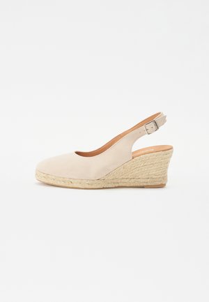 Bézs színű, velúr felsőrésszel készült sarokszandál, nyitott sarkú és orrú, jütéval borított wedgesarkú. Az oldalán található csat lehetővé teszi az állítható illeszkedést.