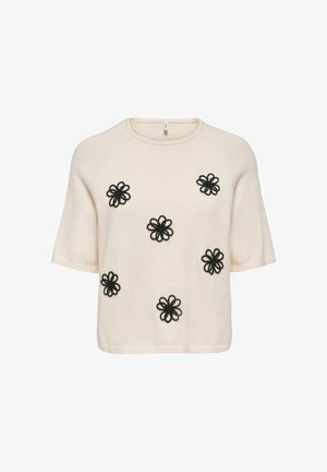Krémový sveter s krátkym rukávom so šiestimi čiernymi vyšívanými kvetmi v podobe slučiek rovnomerne rozmiestnenými na prednej strane.