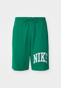 Green cotton shorts with an elastic waistband and drawstring. Features white "NIKE" logo on the left side. Smooth texture, relaxed fit.