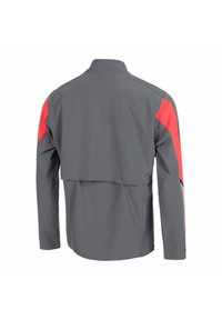 Chaqueta gris de manga larga con acentos rojos en la parte superior de las mangas, un cuello alto y un detalle de abertura suelta en la parte trasera.
