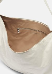 Borsa a spalla in pelle crema con una texture liscia, apertura superiore con zip e interno in satin marrone chiaro, dotato di una piccola tasca con zip.