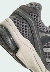Gros plan sur une chaussure de sport grise avec tissu en mesh, surpiqûres synthétiques et semelle coussinée avec le logo de la technologie « Formotion ».