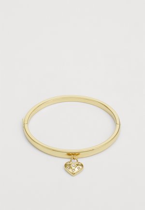 Bracelet jonc en or avec un design lisse et arrondi, orné d'un charm en forme de cœur avec des motifs d'étoiles et une finition polie.