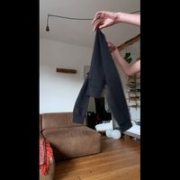 Crna dukserica s dugim rukavima, rebrastim manžetama i opuštenim krojem, držana prema svijetloj pozadini, s mekim tekstilnim uzorkom.