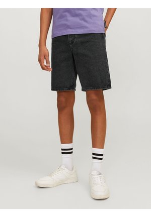Zwarte denim short met een rechte pasvorm, tot de knie. Gepaard met witte sneakers en gestreepte enkelsokken. Casual outfit met minimale details.