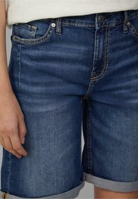 Denim shorts in dark blue with a faded wash. Features include rolled cuffs, five pockets, and contrast stitching on the seams.