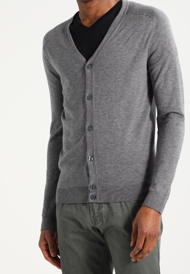 Grå kardigan av mjukt tyg, med V-ringning, femknäppning, ribbade ärmar och en slim fit-design. Bärs över en svart skjorta.